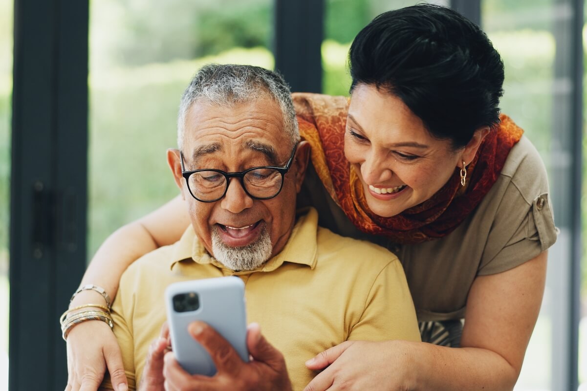 Phone, hug and senior couple in home reading online blog together for news on election campaign