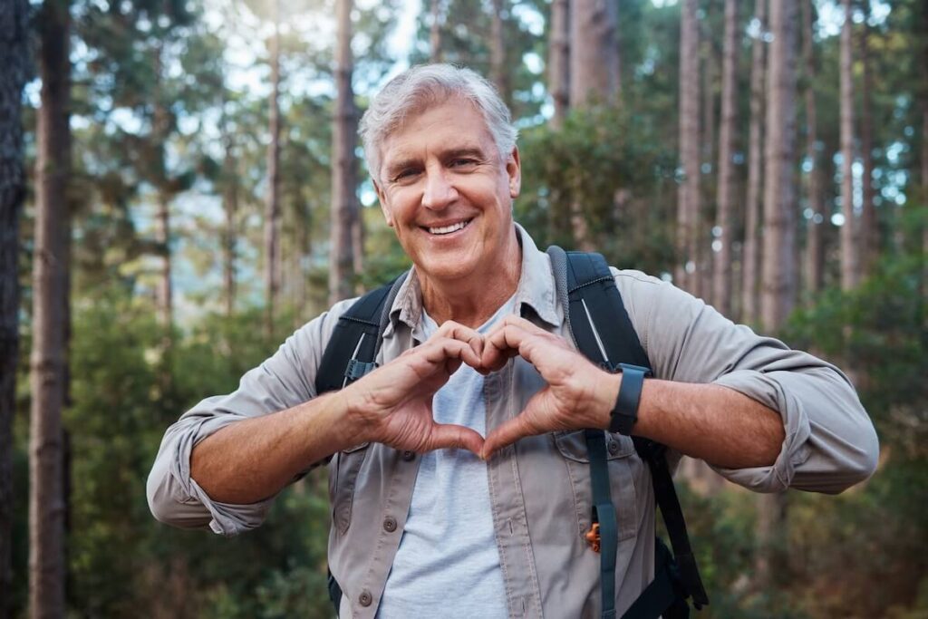 Older adult doing outdoor activity and making a heart sign with his hands