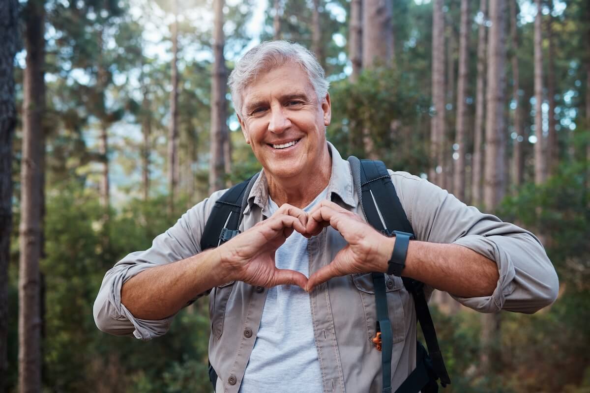 Older adult doing outdoor activity and making a heart sign with his hands
