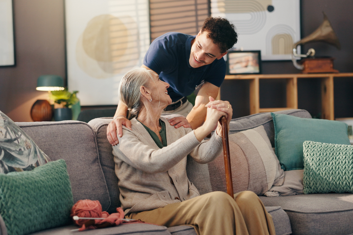 Senior woman, nurse and sofa with assisted living for healthcare service at old age home. Caregiver, medical worker or physiotherapist helping elderly or person with a disability at retirement house.